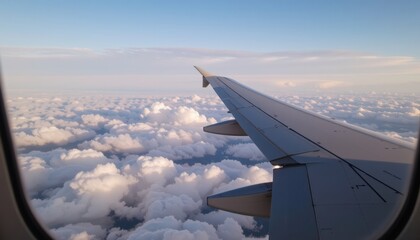 Fototapeta premium Airplane wing above fluffy clouds in a clear sky.