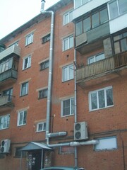 Fototapeta premium Unusual industrial pipe installation on a residential building in a snowy urban environment