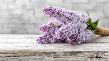Fototapeta premium Beautiful lilac flowers arranged on rustic wooden surface with a soft gray background
