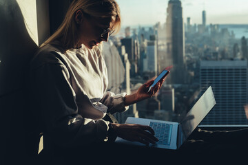 Young distance worker sharing multimedia files via mobile and laptop technology connecting to...