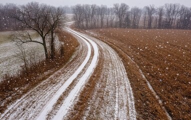 Aerial view of a dirt road winding through a snowy field