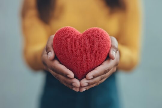 Woman holding red knitted heart symbol of love and compassion