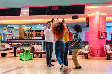 Group of friends giving high fives, celebrating a strike in a vibrant, neon lit bowling alley, enjoying a fun night out