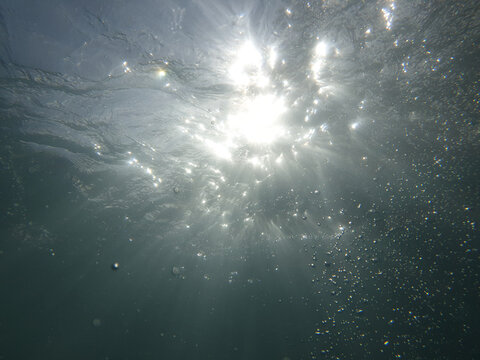 Blue underwater texture with sunrays in backyard swimming pool