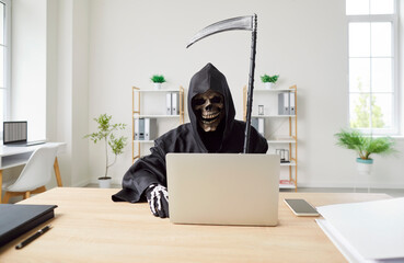 Business man and company employee wearing Halloween grim reaper death costume holding scythe...