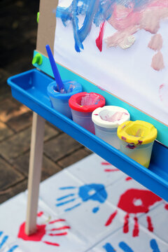 Row of paint pots on easel with mess mat