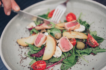 Fresh and colorful salad with seared tuna slices, avocado, and cherry tomatoes on a rustic plate