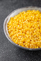 Pasta raw coquillette macaroni appetizer dish organic product fresh tasty gourmet food background on the table rustic food top view copy space