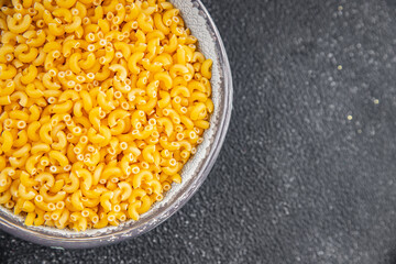 Pasta raw coquillette macaroni appetizer dish organic product fresh tasty gourmet food background on the table rustic food top view copy space