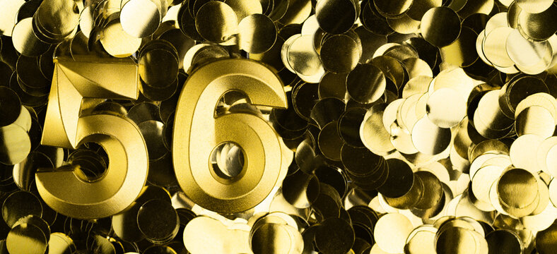 Golden number fifty-six 56 candle on shiny yellow confetti background. Festive backdrop for fifty-sixth birthday, anniversary, or celebration. Bright greeting card with space for text.