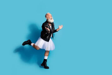 Photo of senior nonbinary man dancing look empty space feel amazed in female clothes isolated blue color background