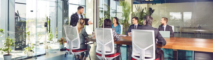 Office business team talking at big meeting table in modern conference room, brainstorming in...