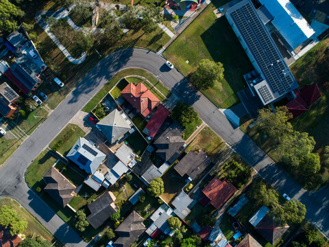 Aerial view of road looping through suburb in town on sunlit morning in summer