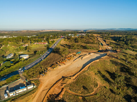 Machinery on worksite lined up in morning light ready to continue construction on bypass road
