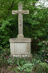 Stone cross standing in lush green cemetery