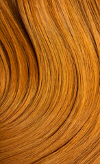 Red hair close-up as a background. Women's long orange hair. Beautifully styled wavy shiny curls. Hair coloring bright shades. Hairdressing procedures, extension.