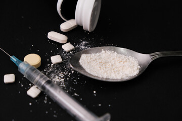 Narcotic drugs with syringe and spoon, isolated dark background