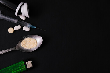 Narcotic drugs with syringe and spoon, isolated dark background