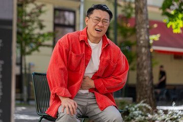 Asian middle-aged man feeling sudden strong abdominal stomach ache, gastritis problem outdoors....