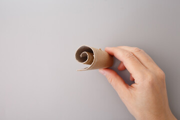 step in creative project, hand holding a piece of cardboard that has been rolled up. repurposed...