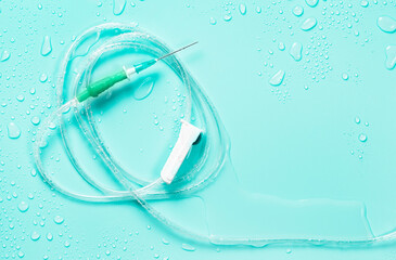Empty dropper with sharp needle and feed regulator on blue background wet with medicine.