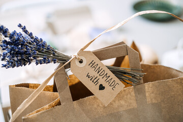Close-up of a brown paper bag with a handwritten tag reading Handmade with love and a sprig of...