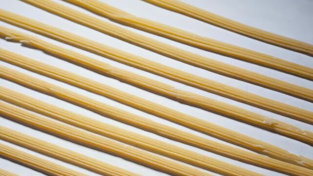 Close-up of several strands of cooked spaghetti lying parallel to each other on a white surface creating a repeating pattern.
