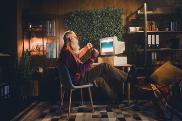 Elderly programmer celebrates successful code in cozy home office environment with classic computer...
