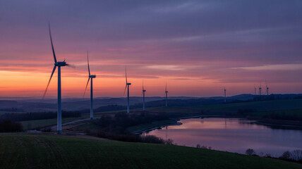 Obraz premium Wind turbines spin slowly against a colorful dusk horizon!