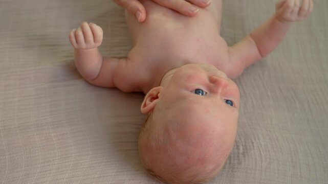 A mother gently applies special cream to treat the delicate skin of her newborn baby. A tender and caring moment focused on soothing and healing the baby's skin with love and attention. Slowmotion