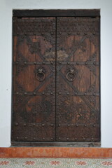 Solid old wooden double door with ornate metal handles