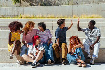 Fototapeta premium Multiethnic group of young friends meeting and having fun outdoors - Multiracial happy and stylish teen students bonding in the city, concepts about youth, teenagers lifestyle and diversity
