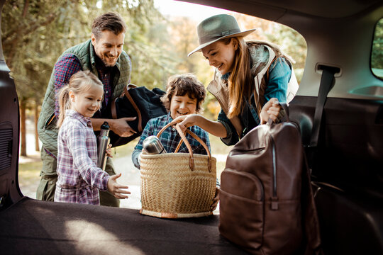 Family packing car trunk together for weekend road trip adventure