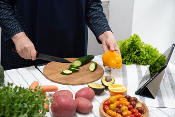Mature woman cooking online recipe with tablet. Meal Time