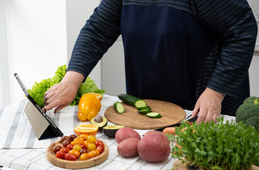 Mature woman cooking online recipe with tablet. Meal Time