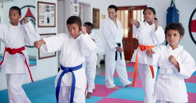 Kids, learning karate and training in class with instructor for fight, fitness or self defense. Students, children and people practice martial arts, kick and exercise for lesson with teacher in dojo