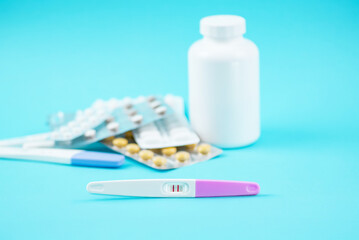 Pregnancy test with two stripes on pastel blue background. Positive result. Vitamins for mother and...