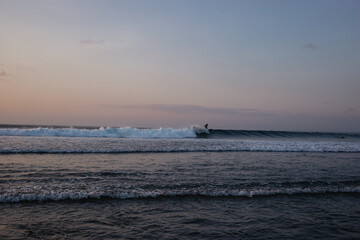 Surfer catches waves in the ocean at sunset in the evening. Surfer rides a shortboard
