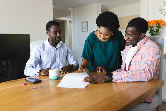 Couple and african american real estate advisor discussing new home at kitchen table, with tablet