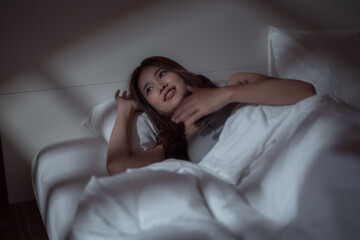 Young Asian woman lying in bed at night, struggling with insomnia, unable to find rest as racing...