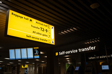 Airport terminal showing direction signs for baggage, arrivals, and transfer gates