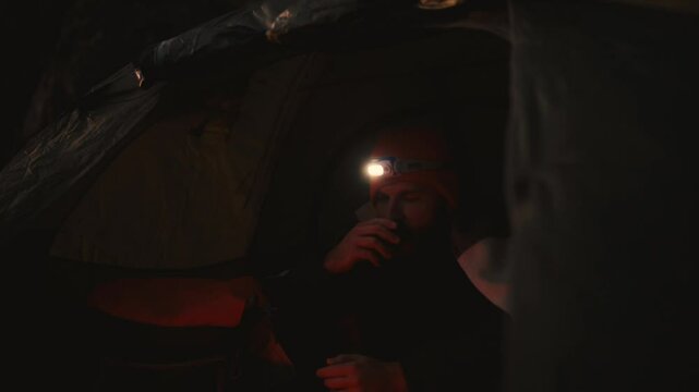 Cozy Camping Moment in Iceland: Man Enjoys Hot Tea Inside Tent
