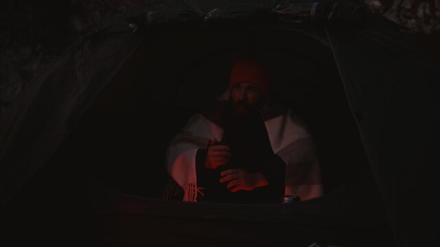 Cozy Camping Moment in Iceland: Man Enjoys Hot Tea Inside Tent