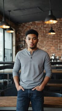 Young adult making a kissy face in a cafe with brick wall and industrial lighting, wearing casual clothing.