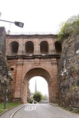 Fototapeta premium Historic stone archway bridge with cobblestone road in cityscape, architectural heritage concept