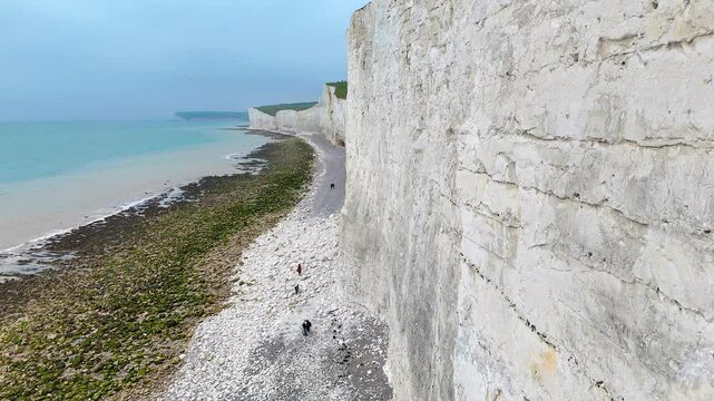 Panoramic view of the iconic white chalk cliffs of England with a stony beach and turquoise sea, ideal for travel, tourism, nature, and adventure concepts in commercial campaigns