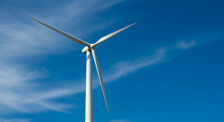 White Wind Turbine Against a Clear Blue Sky and Cirrus Clouds Generating Renewable Energy