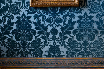 Blue velvet wallpaper and gold frames with paintings