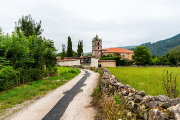 A scenic road winds toward an ancient church in Cantabria Saja River Valley, Spain.