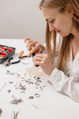 Small Business. A jewelry designer carefully crafting handmade accessories using beads, pliers, and metal parts. Close-up of hands creating elegant jewelry pieces	